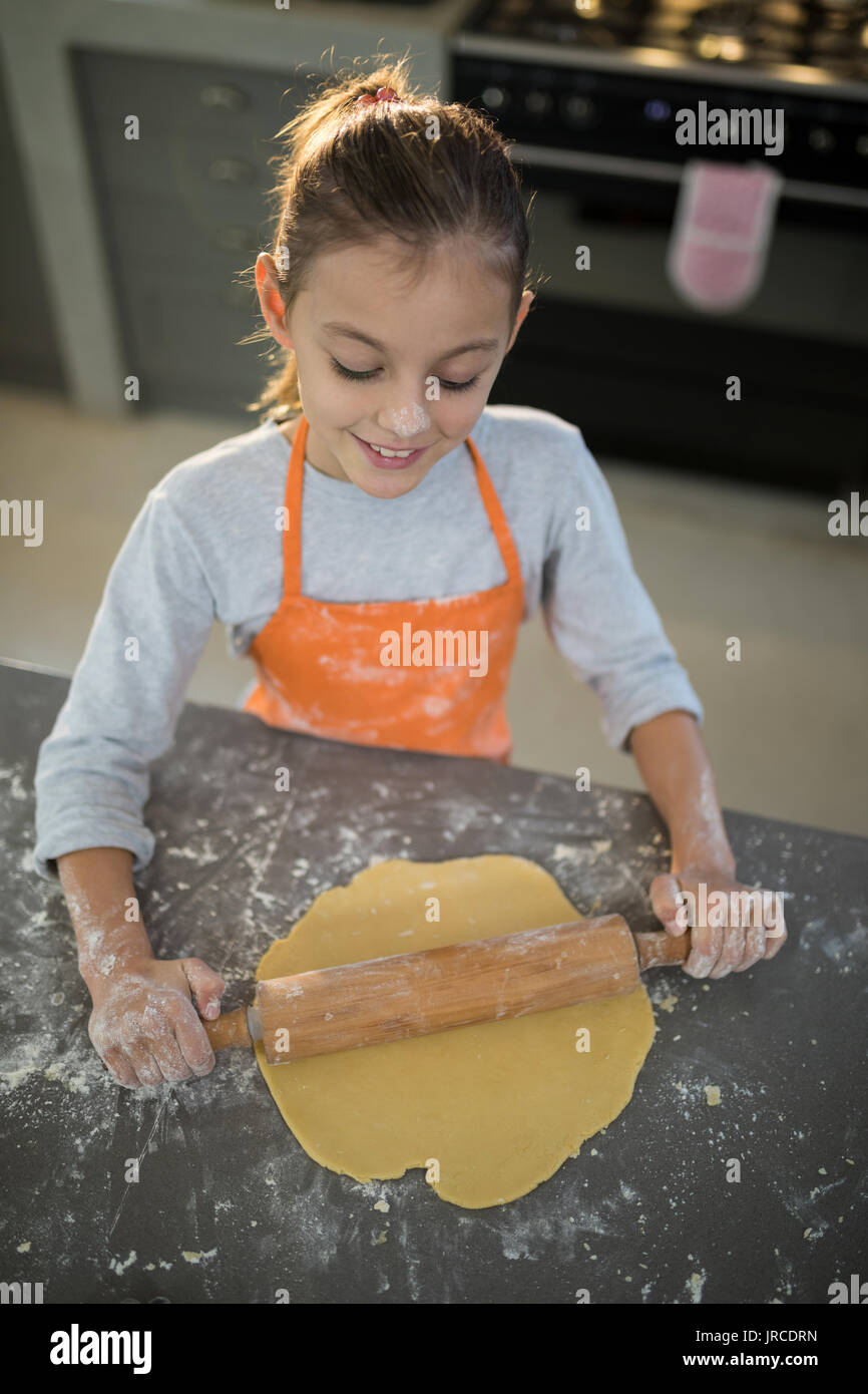 In der Nähe von kleines Mädchen Abflachung Teig auf der Arbeitsplatte in der Küche Stockfoto