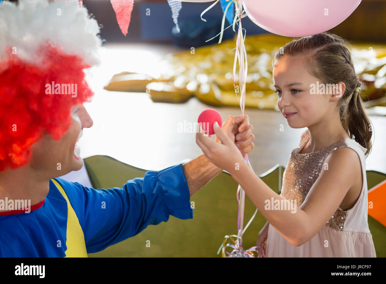 Clown und Mädchen interagieren während der Geburtstagsfeier zu Hause Stockfoto