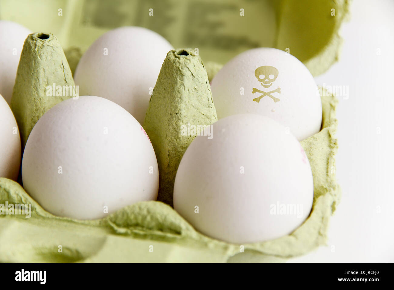 Eier in ein Paket mit ein Ei mit einem giftigen Gefahr symbol Schädel und Knochen bemalt. Bild Konzept für Lebensmittel Verunreinigungen, verdorbene Eier Skandal. Stockfoto