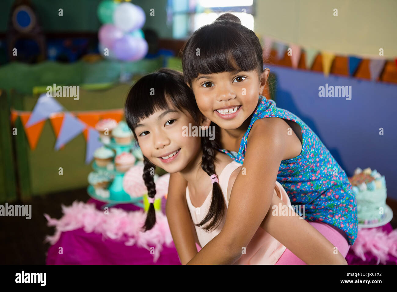 Mädchen mit piggyback Ride an ihre Freundin während der Geburtstagsfeier zu Hause Stockfoto