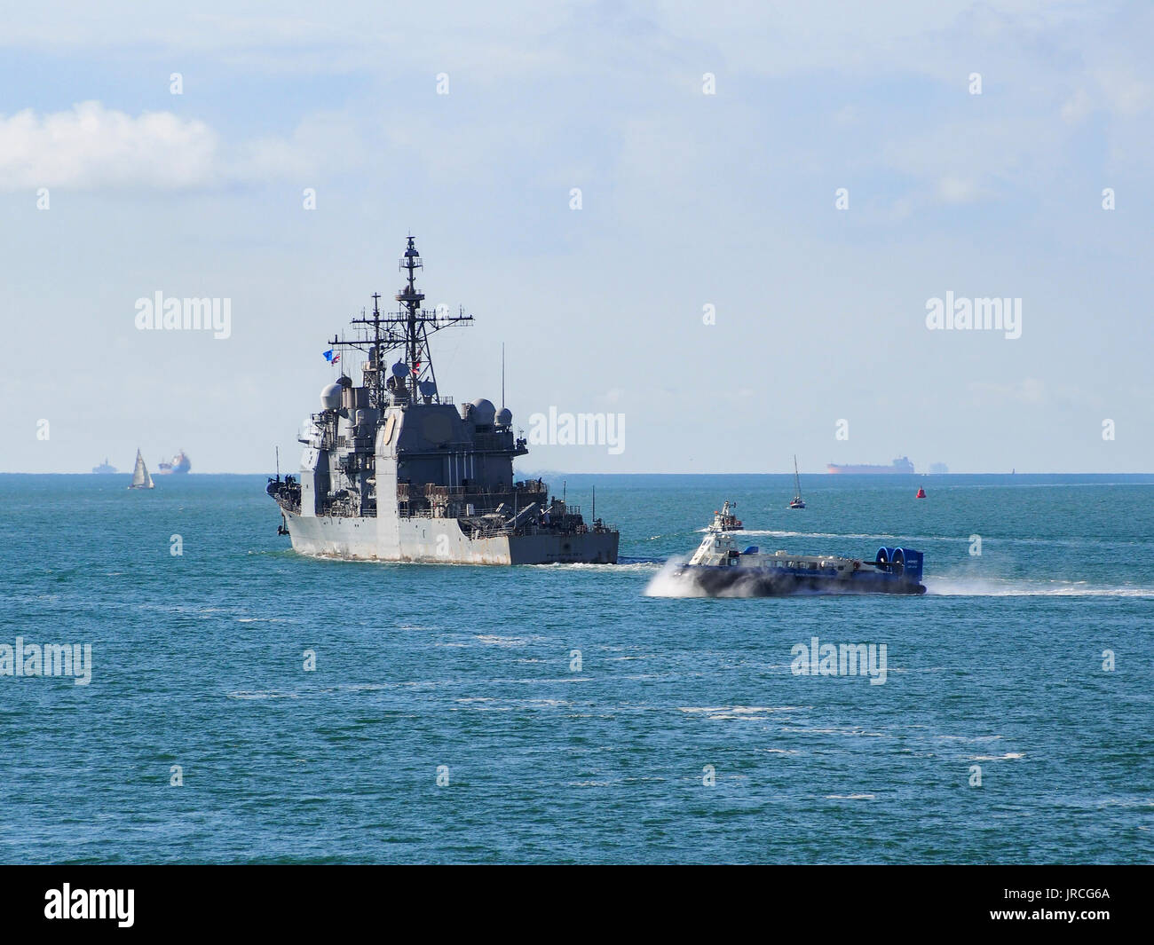 Die USS Philippinische übergibt die Isle of Wight hovercraft als sie Meer Segel in den Solent von Portsmouth Harbour, England. Stockfoto