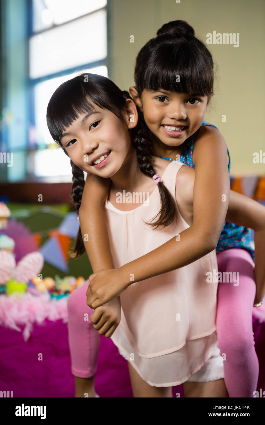 Mädchen mit piggyback Ride an ihre Freundin während der Geburtstagsfeier zu Hause Stockfoto