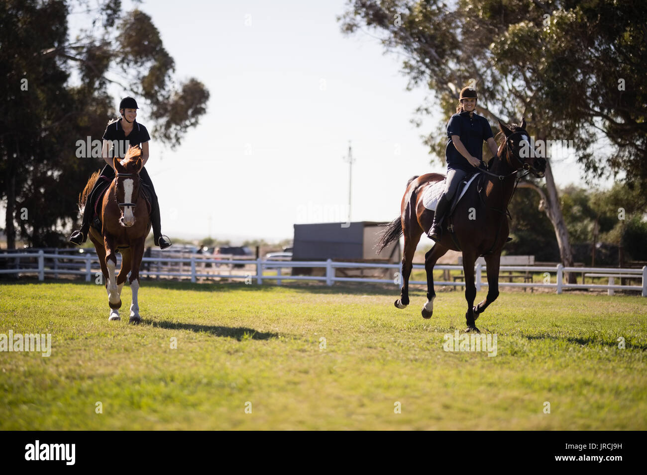 Junge Frauen Reiten an Equestrian Center Stockfoto