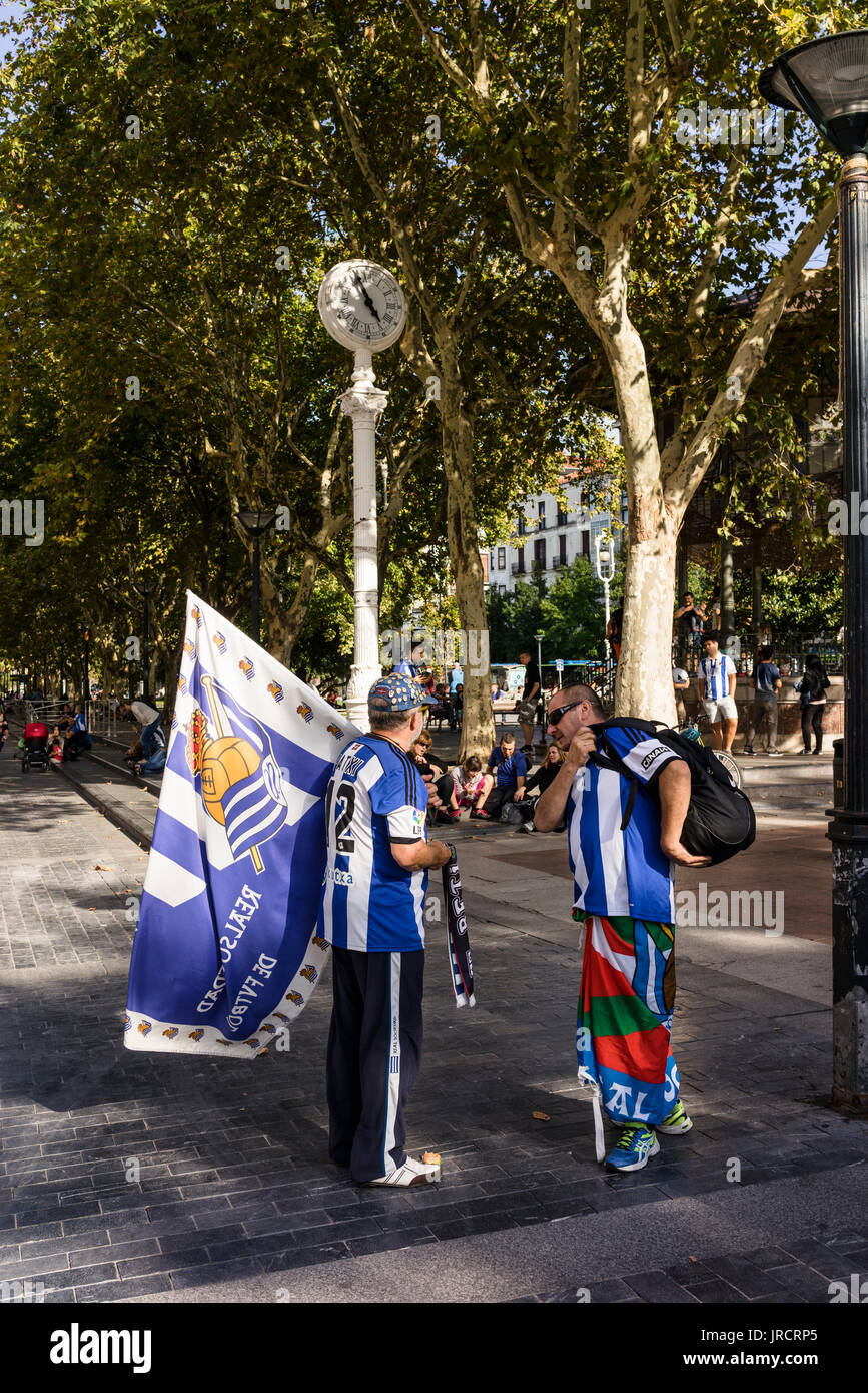 Real Sociedad-Fans auf dem Weg zum Stadion Anoeta, das Derby gegen Athletic Bilbao zu spielen. Gekleidet mit Home Trikots und baskischen Flaggen Stockfoto