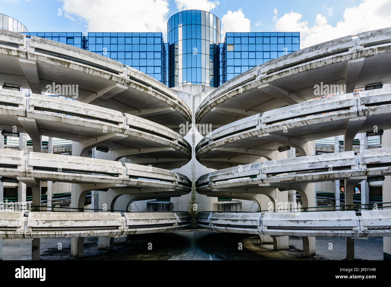 Spiralförmige Rampen eines alten maroden Beton Parkplatz mit einem Glas Bürogebäude im Hintergrund. Stockfoto