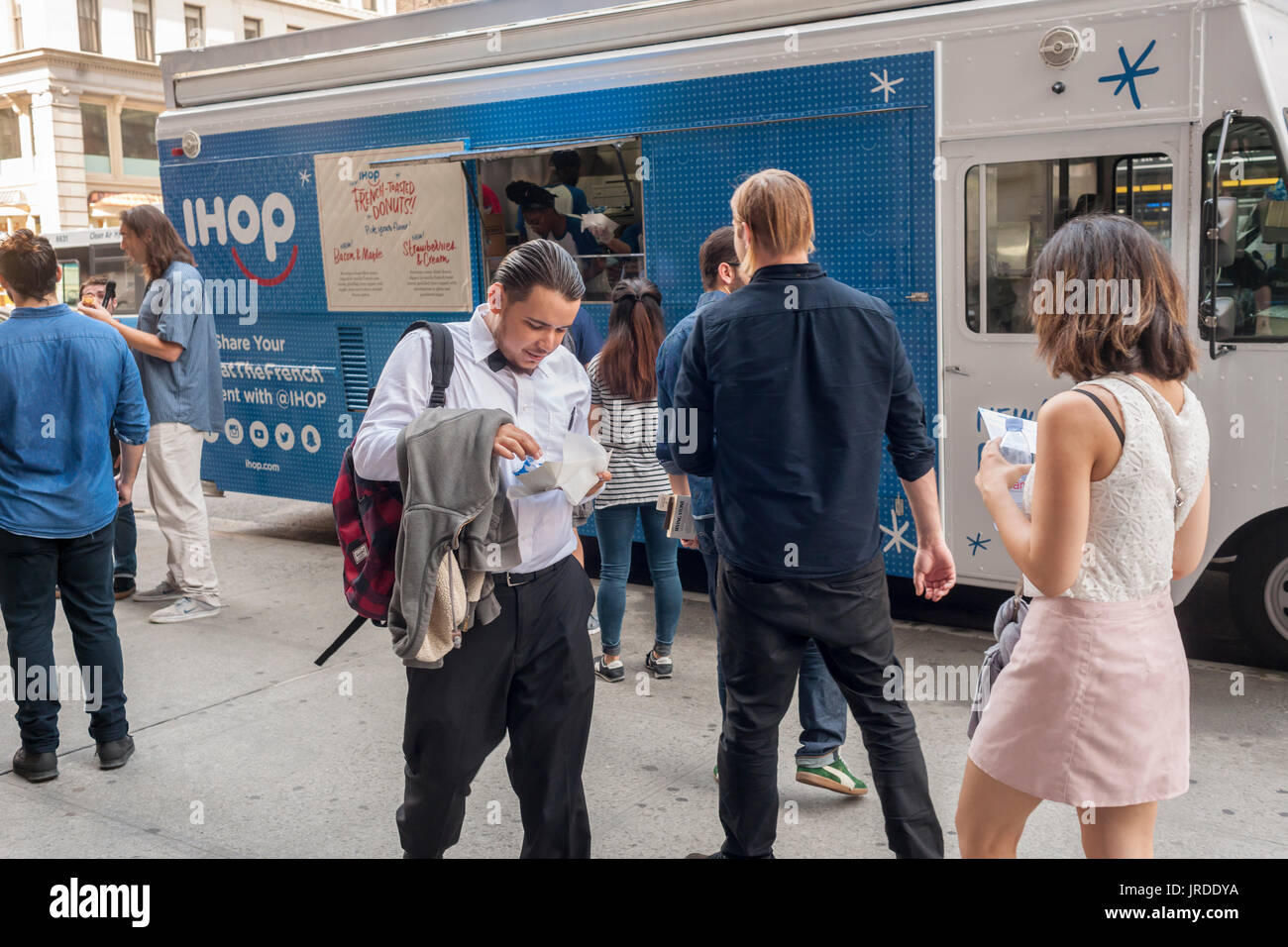 Hungrige Feinschmecker Line-up an ein IHOP gebrandmarkt Imbisswagen in der Flatiron Nachbarschaft von New York für kostenlose Proben von ihren neuesten Angebot, frittierte Krapfen in Vanille French Toast Teig getaucht und mit herzhaften und süßen Belag fertig. Die International House of Pancakes-Produkte haben entweder eine Ahorn-Speck-Glasur oder eine Erdbeere und eine Creme. Eine dritte Sorte Apfel Krapfen ist nur in ihren Restaurants verfügbar. iHOP ist eine Marke der DineEquity die auch Applebees besitzt. Sie steuern über 3700 Restaurants in die kombinierte Ketten, 99, die Prozent davon Franchise sind. (© Richard B. Levine) Stockfoto