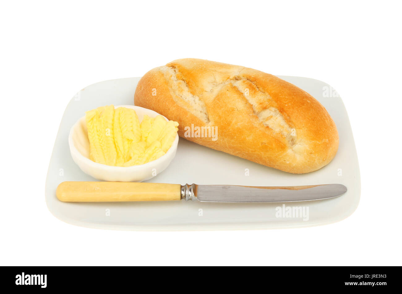 Brötchen Messer und Butter auf einer Platte gegen Weiße isoliert Stockfoto