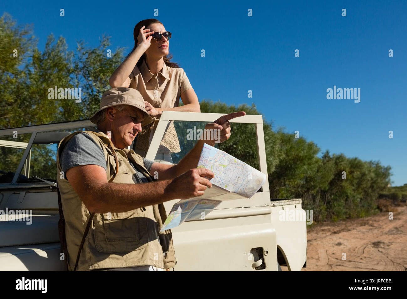 Mann, während die Karte mit Frau in Off Road Fahrzeug auf Feld Stockfoto