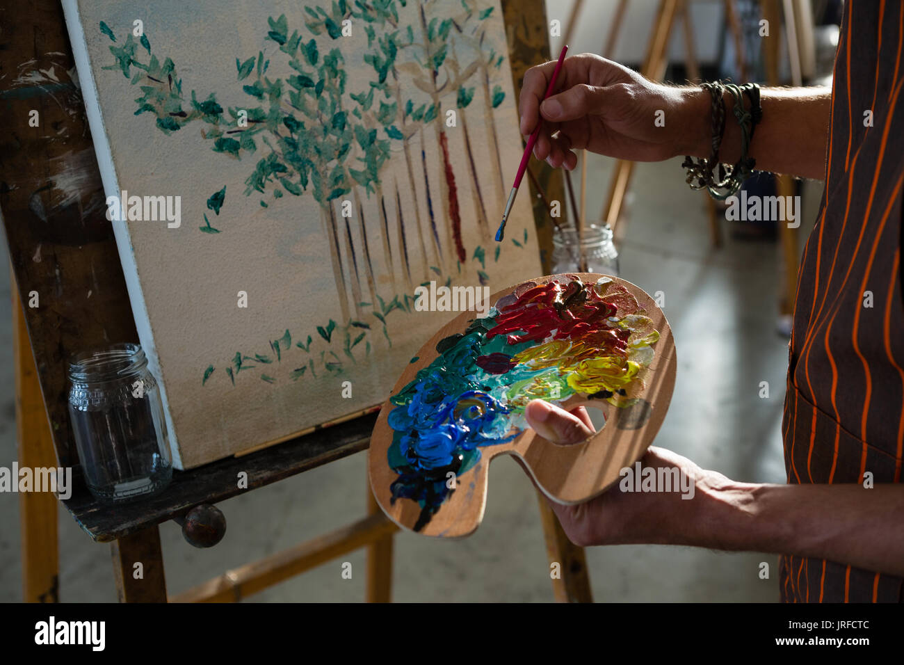 Zugeschnittenes Bild des Künstlers paining auf Leinwand im Kunstunterricht Stockfoto