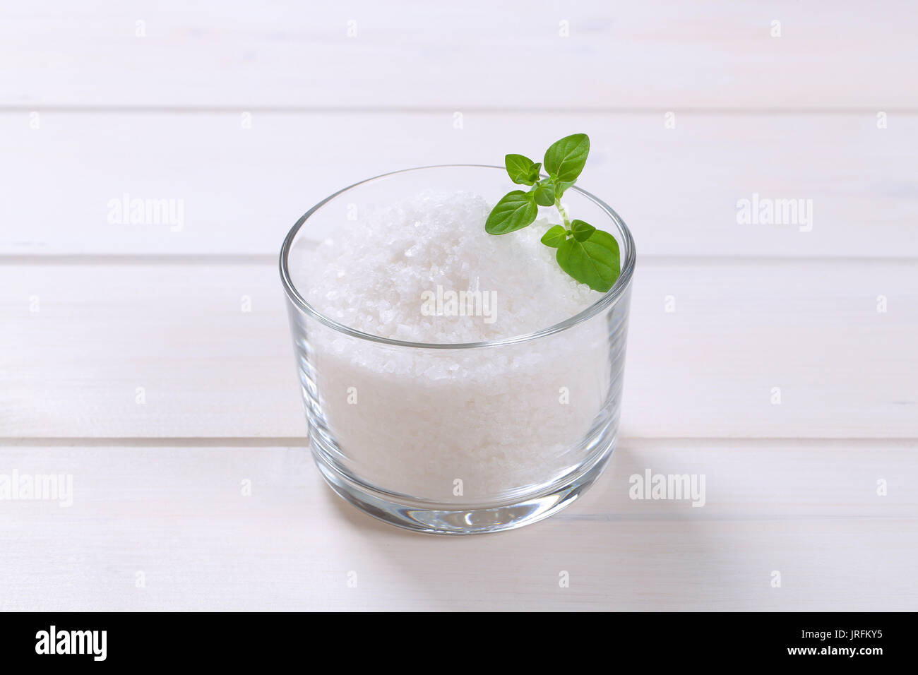 Glas grobkörniges Meersalz auf weißem Holz- Hintergrund Stockfoto