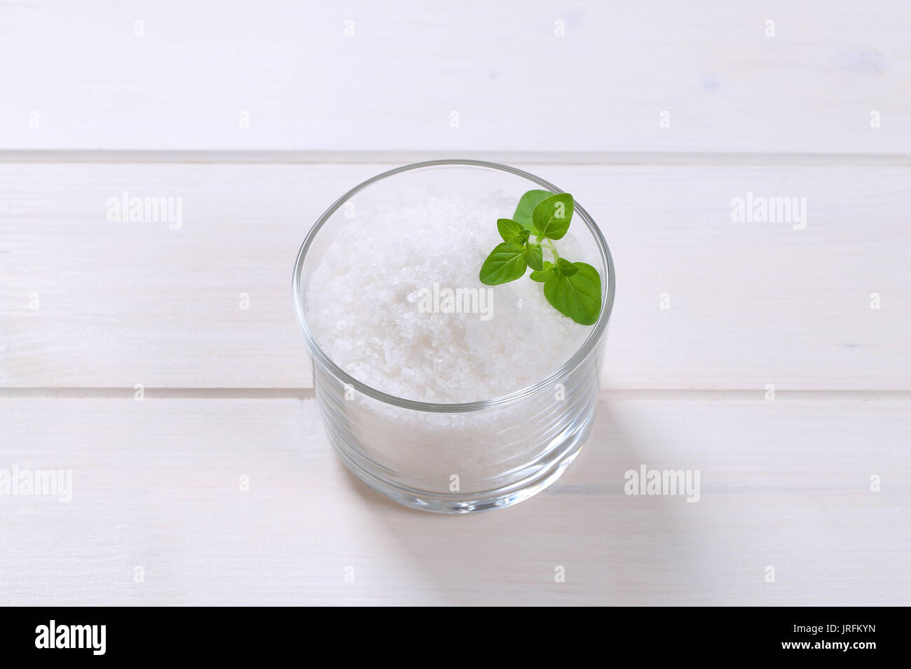 Glas grobkörniges Meersalz auf weißem Holz- Hintergrund Stockfoto