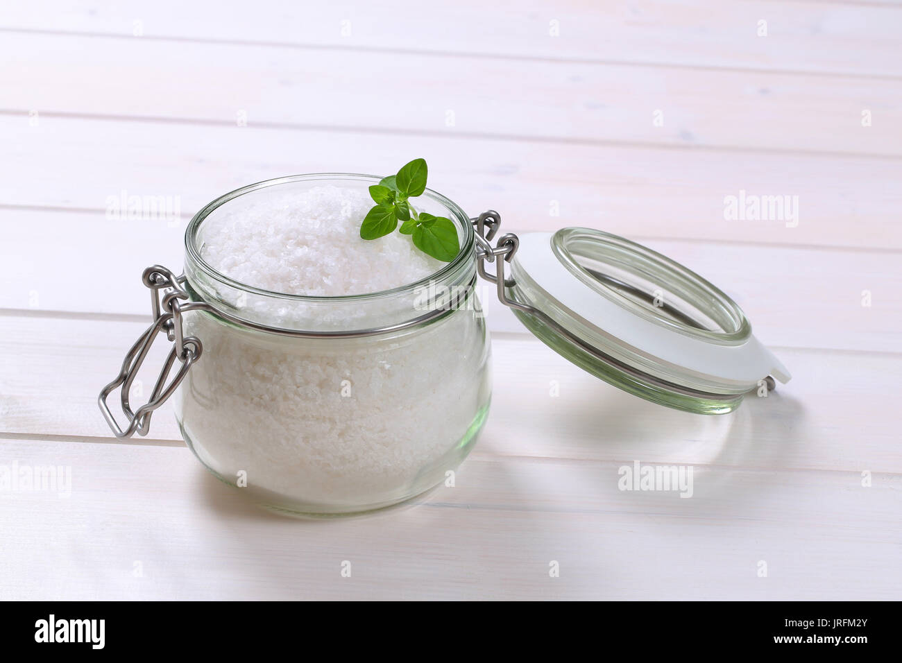 Jar von grobkörnigem Meersalz auf weißem Holz- Hintergrund Stockfoto