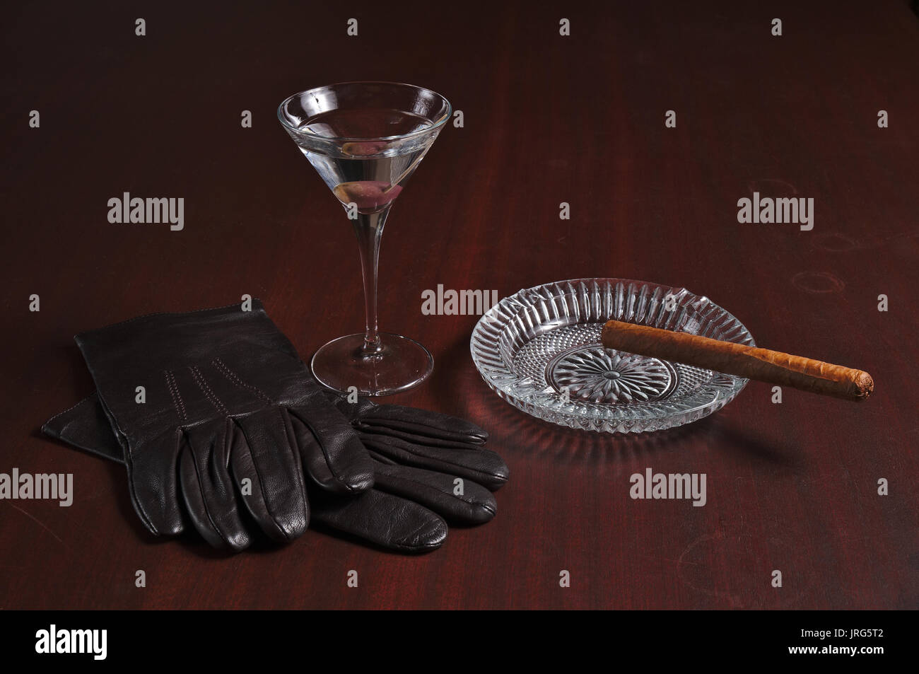 Zigarre, leder handschuhe und Martini auf einen hölzernen Tisch. Vintage und Lifestyle Themen Stockfoto