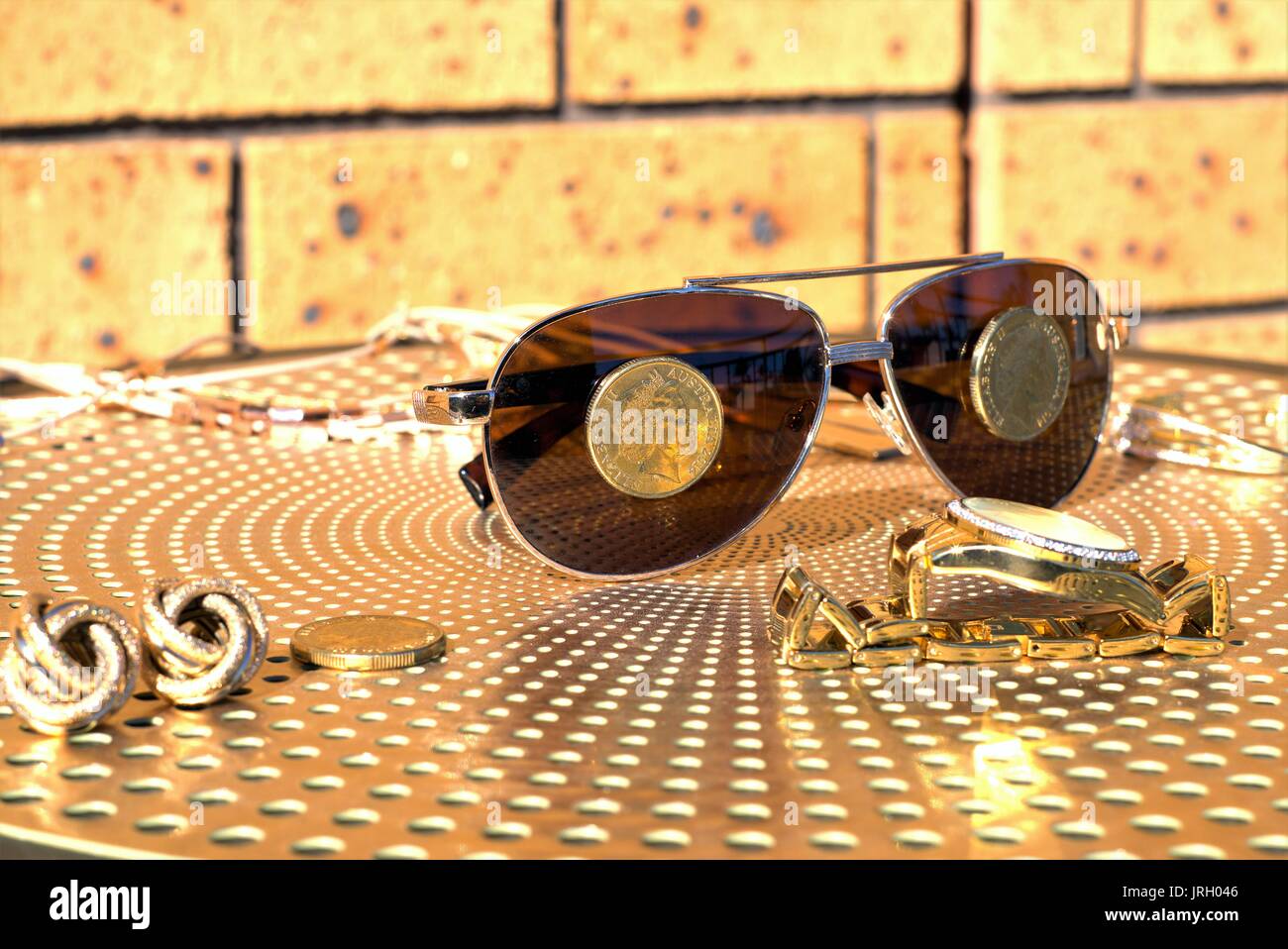 Australische Münzen auf eine Sonnenbrille. Australische 1 Dollar Münzen auf Sonnenbrillen, Gold Diamond Watch und anderen Gold Schmuck auf Tisch Stockfoto