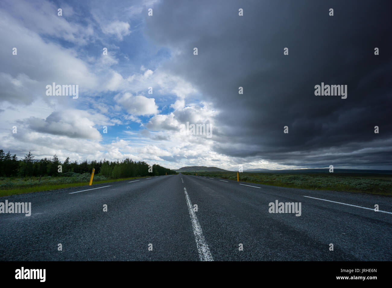 Island - Leere Autobahn unter dunklen Gewitterwolken Stockfoto