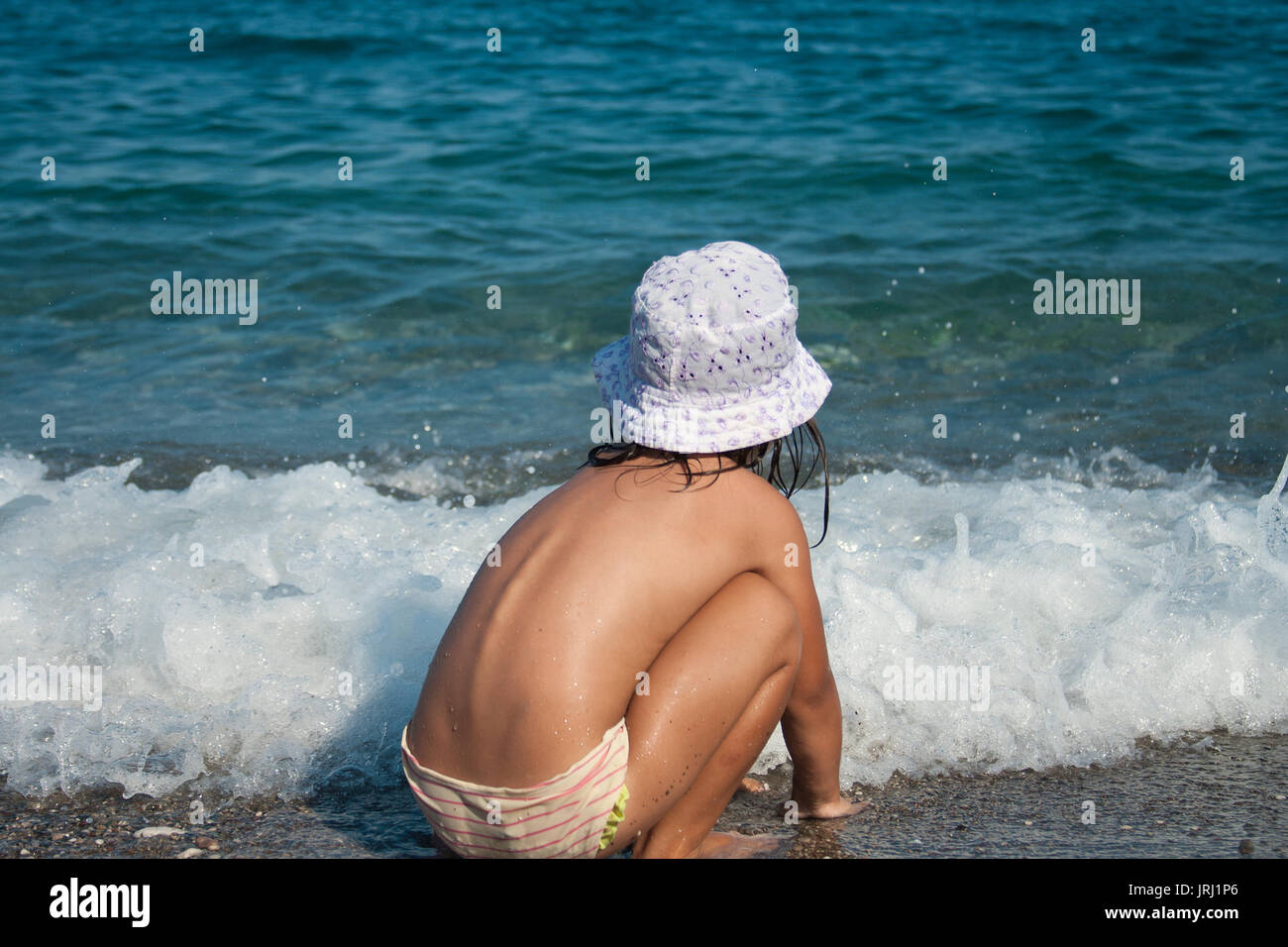 Drei Jahre alten Mädchen spielt mit Wellen am Strand. Stockfoto