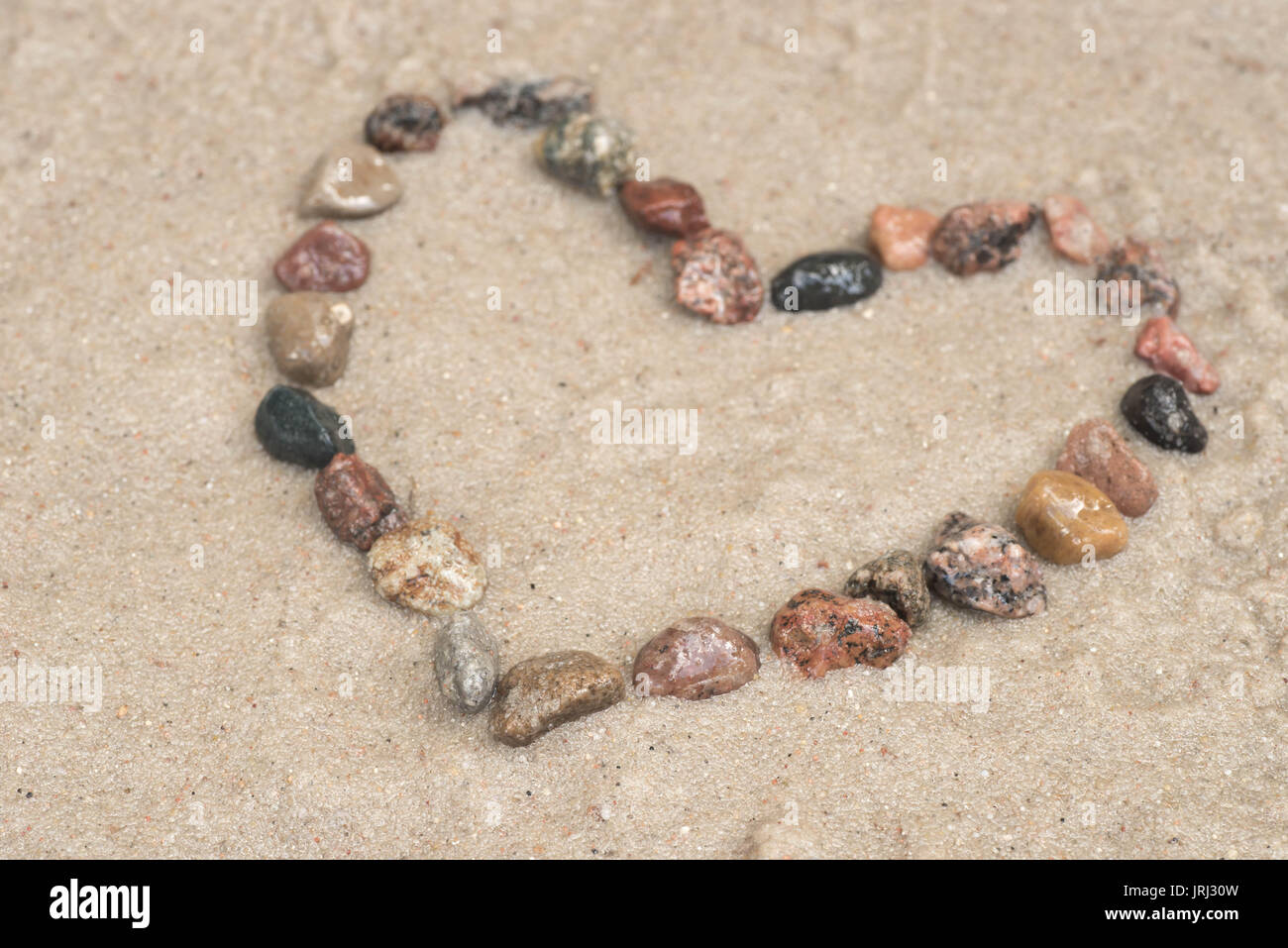 Kiesel zeigende Pfeil auf Sand Hintergrund Stockfoto