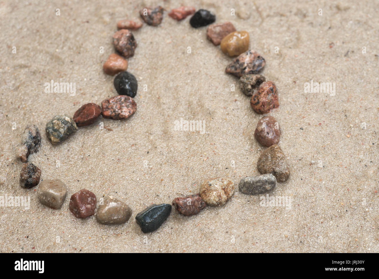 Kiesel zeigende Pfeil auf Sand Hintergrund Stockfoto