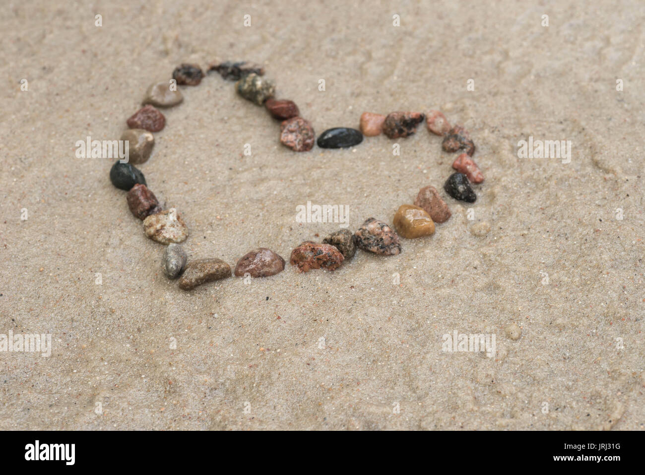Kiesel zeigende Pfeil auf Sand Hintergrund Stockfoto