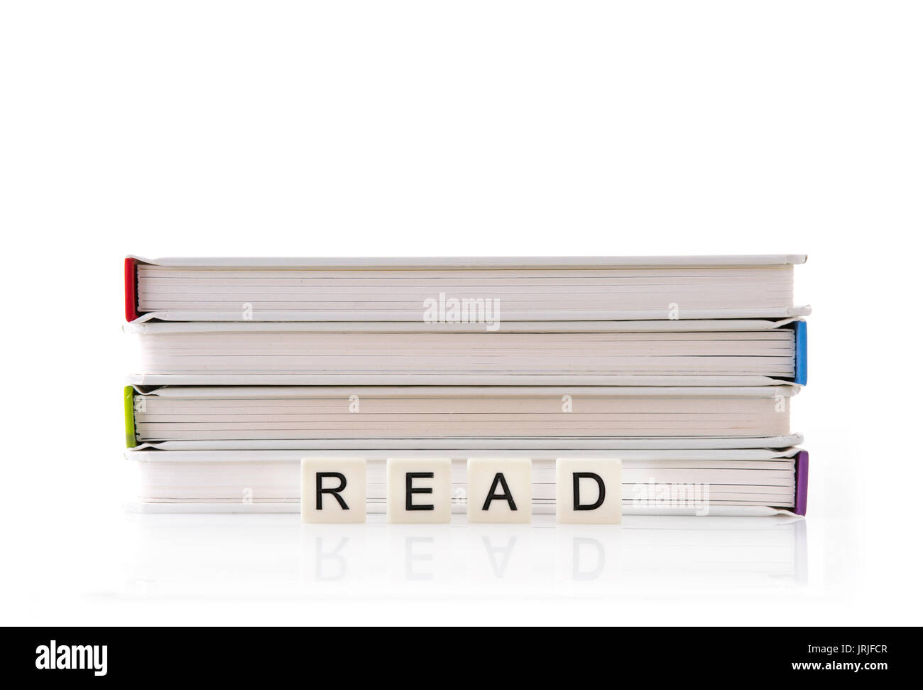 Stapel Bücher mit Lesen buchstabiert auf Wort Fliesen auf weißem Hintergrund Stockfoto