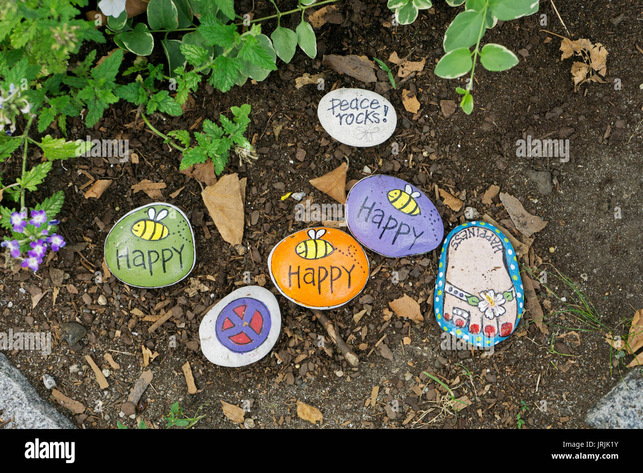 Bemalte Steine mit fröhlichen Nachrichten in einem Garten gemalt und durch die Anhänger von Sri Chinmoy gepflegt. In Jamaica, Queens, New York Stockfoto