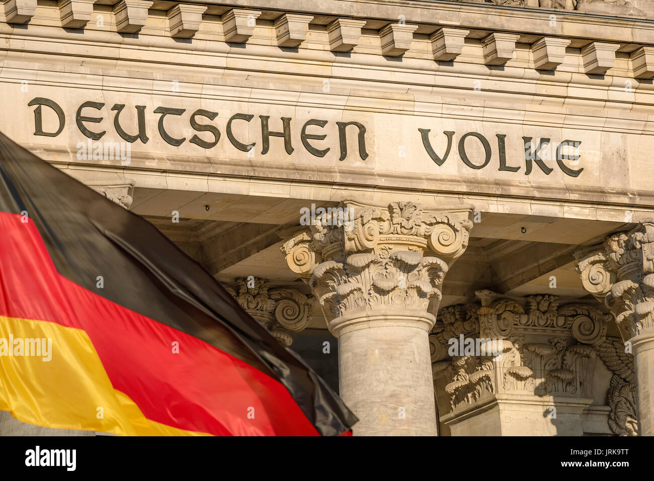 Berliner Reichstag Vorderseite, Detail der Inschrift an der Fassade der Deutschen Parlament Gebäude (der Bundestag) in Berlin mit Fahne im Vordergrund. Stockfoto