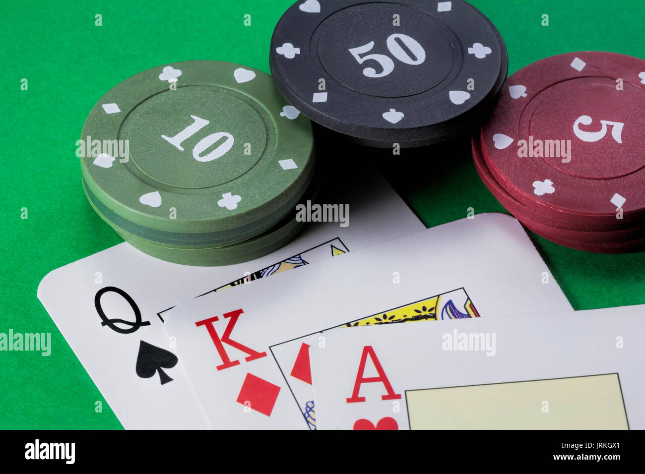 Karten Poker Deck Englisch, Pik Dame, Rot König von Diamanten und Herz Ass neben Tabs von 10, 50 und 5 auf grünem Hintergrund Stockfoto