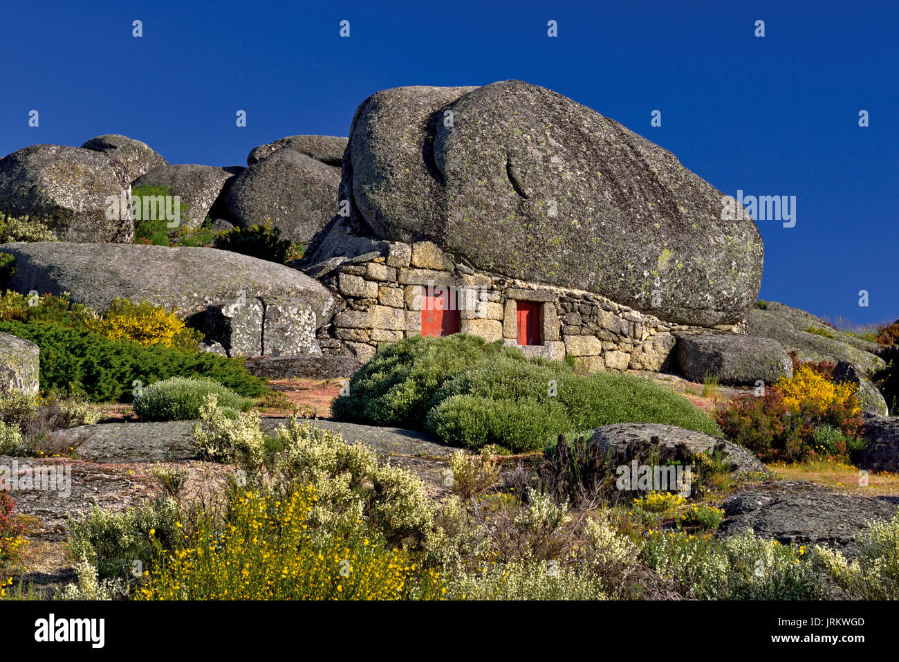 Kleines Haus aus Stein unter riesigen Granitfelsen Stockfoto