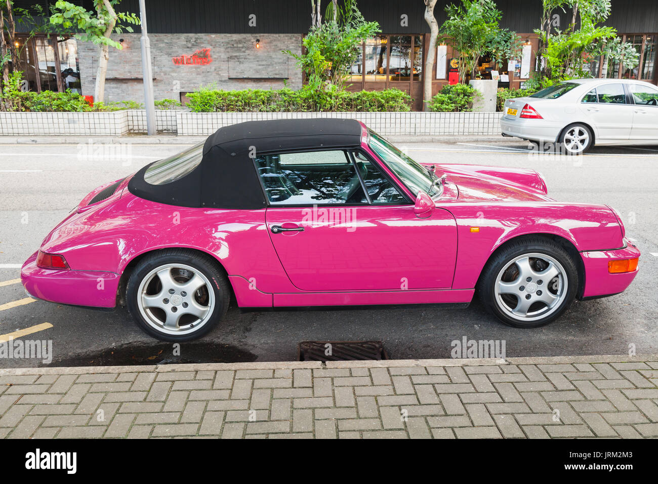Hongkong - Juli 10, 2017: Rosa Porsche 964 Carrera 2 Cabriolet, klassischen deutschen Sportwagen steht auf der Straße in Hong Kong City, Seitenansicht Stockfoto Hongkong - Juli 10, 2017: Rosa Porsche 964 Carrera 2 Cabriolet, klassischen deutschen Sportwagen steht auf der Straße in Hong Kong City, Seitenansicht Stockfoto