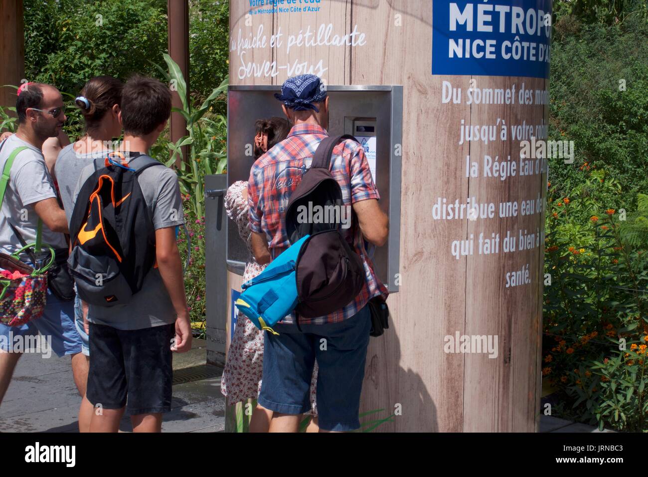 Touristen, die frisches Trinkwasser vom Wasserkiosk, Nizza, Frankreich, bekommen Stockfoto