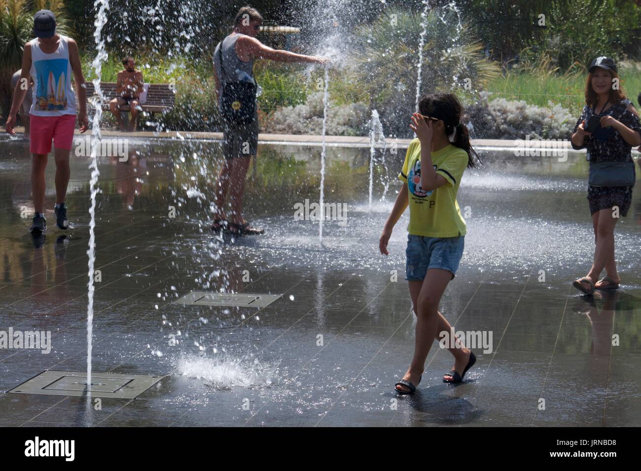 Touristen, die Spaß haben, in Wasserfontänen am Massena-Platz, Nizza, Frankreich zu planschen Stockfoto