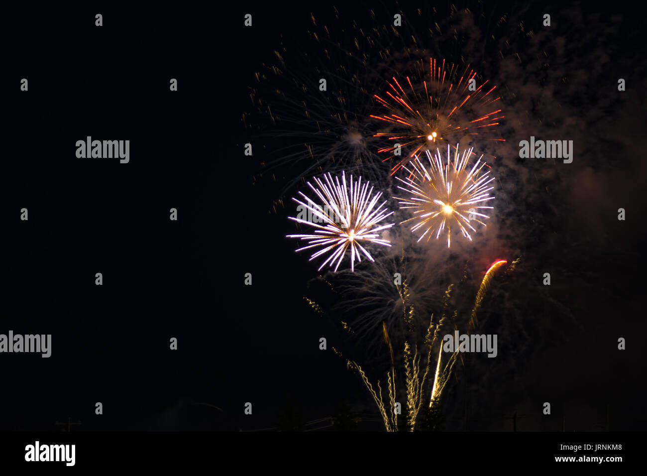 Brillantes Feuerwerk von roten, gelben und weißen Farben, gegen einen schwarzen Himmel während ein Abend der Feier ein nationaler Feiertag. Stockfoto