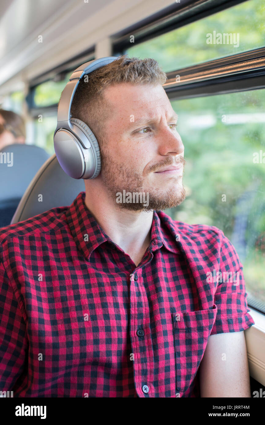 Junger Mann Hören von Musik über Kopfhörer während der Fahrt zur Arbeit Stockfoto