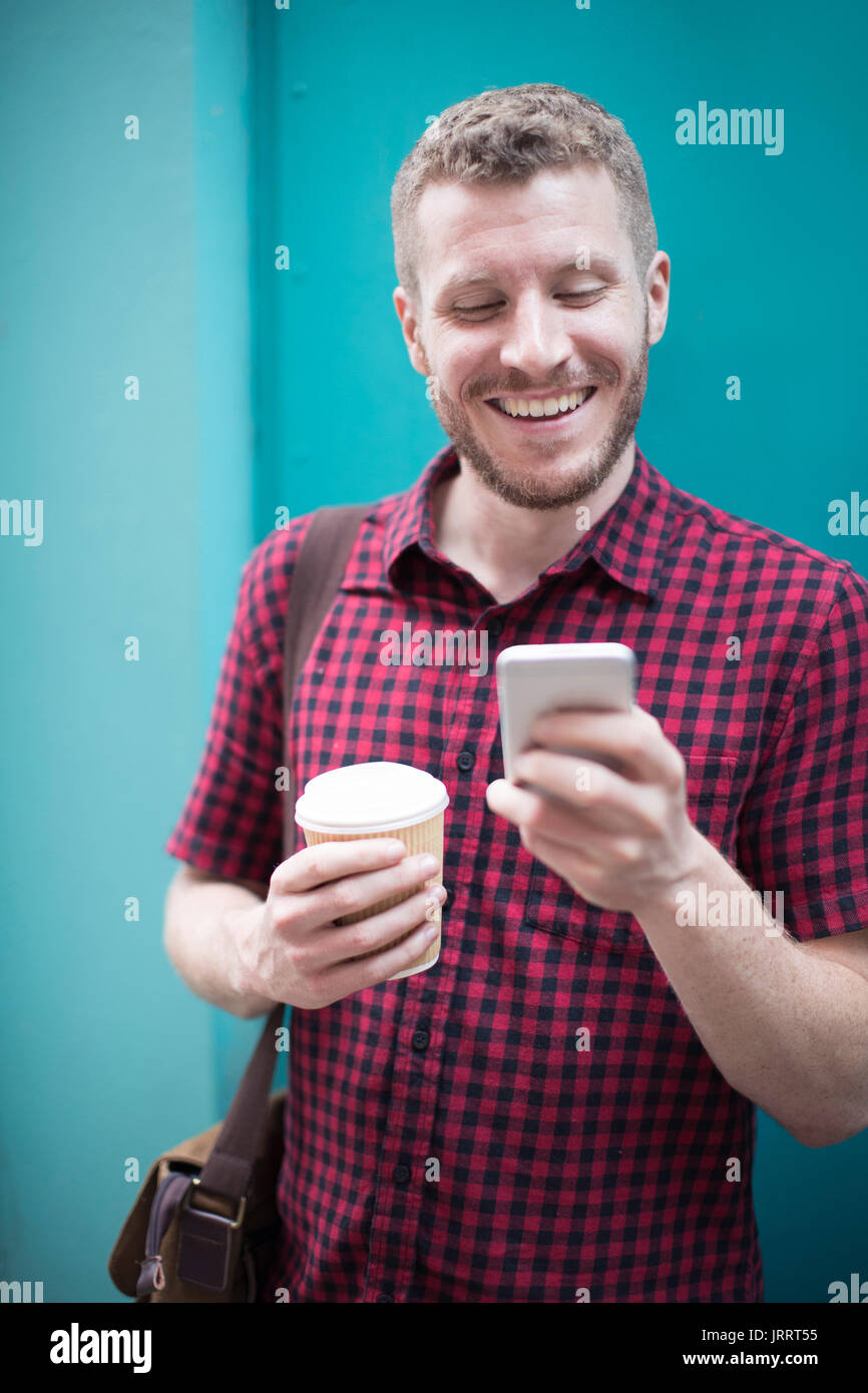 Mann, der vor der blauen Tür Lesen von SMS Stockfoto