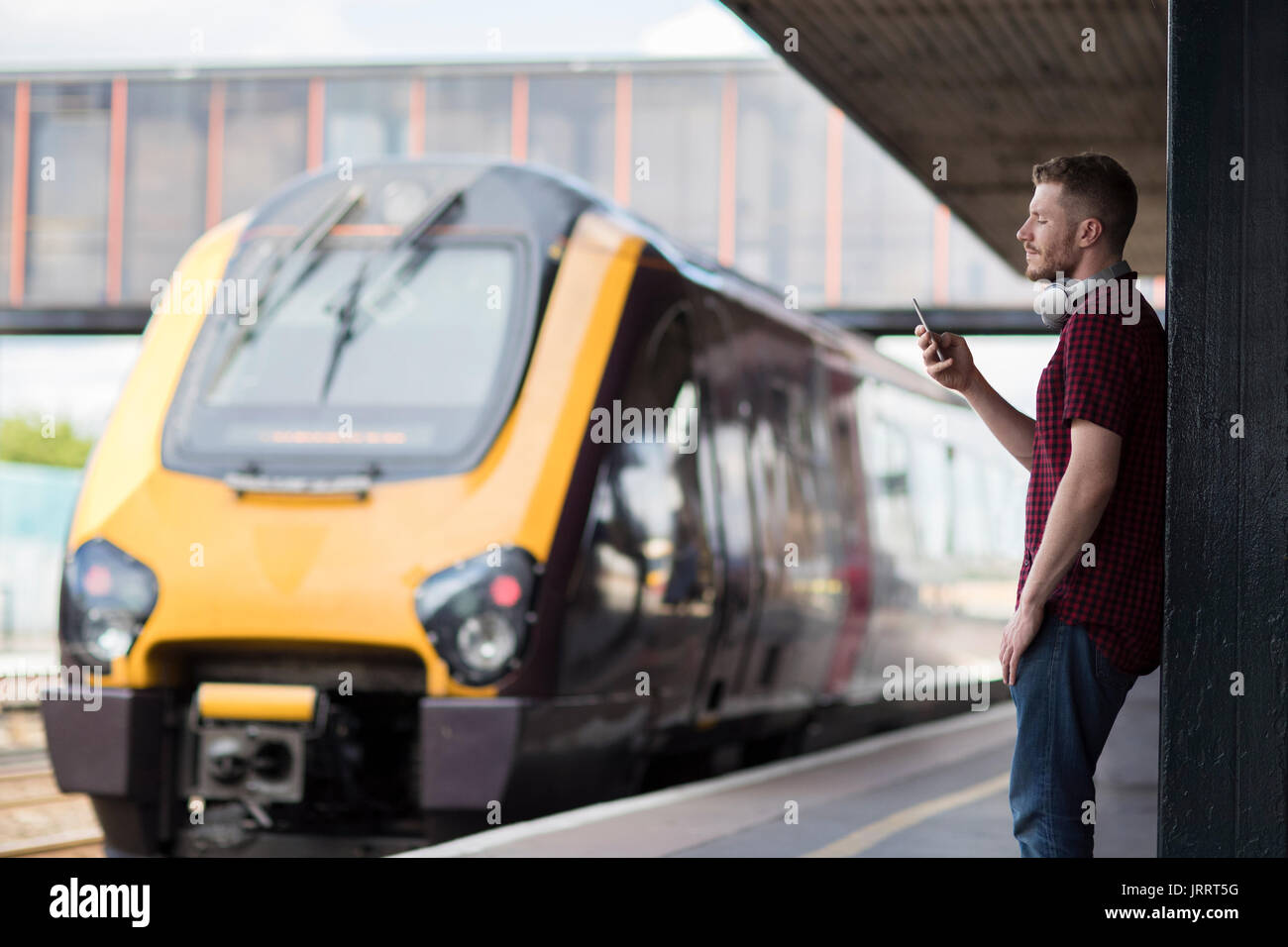 Mann am Bahnhof mit Handy auf Plattform Stockfoto