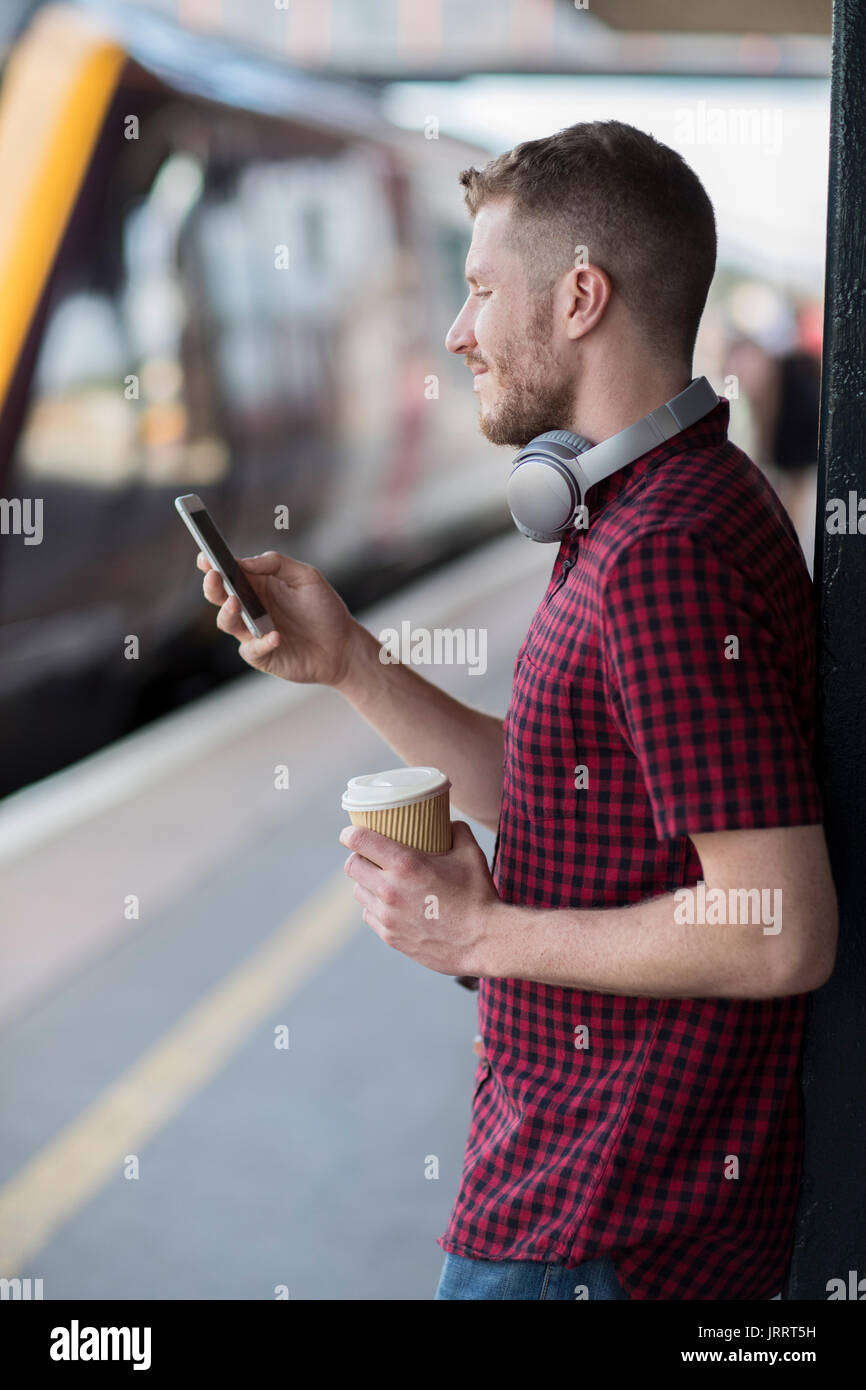 Mann am Bahnhof mit Handy auf Plattform Stockfoto