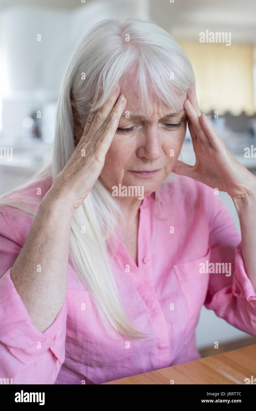 Reife Frau zu Hause leiden unter Kopfschmerzen. Stockfoto