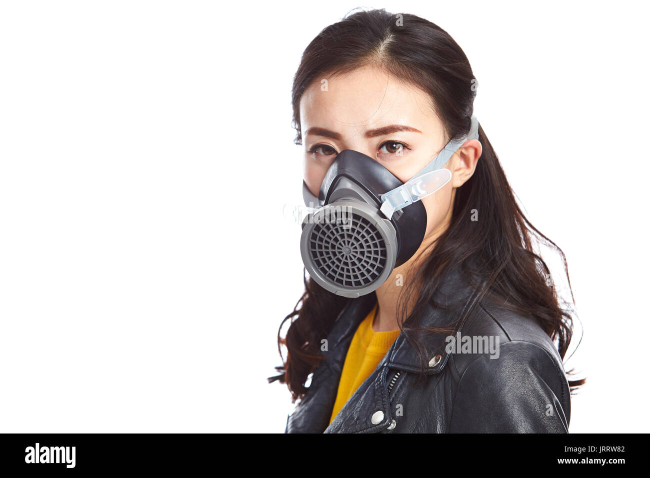 Junge asiatische Frau in schwarzem Leder Jacke tragen eine Gasmaske an Kamera suchen, auf weißem Hintergrund. Stockfoto