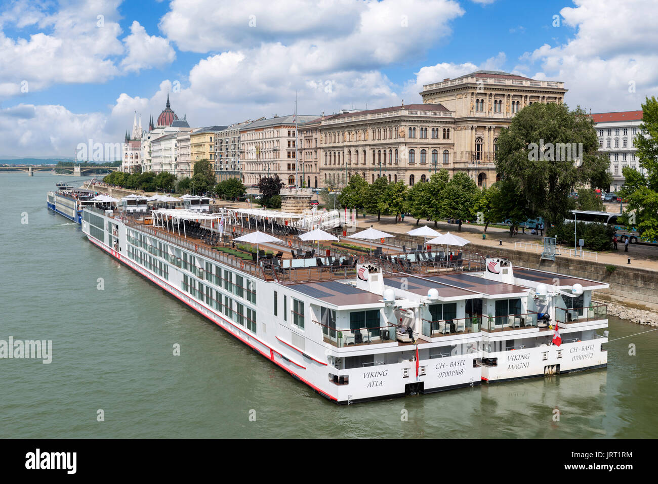 Viking River Cruises Kreuzfahrtschiffe auf der Pester Seite der Donau mit dem Parlament Gebäude in der Ferne, Budapest, Ungarn Stockfoto