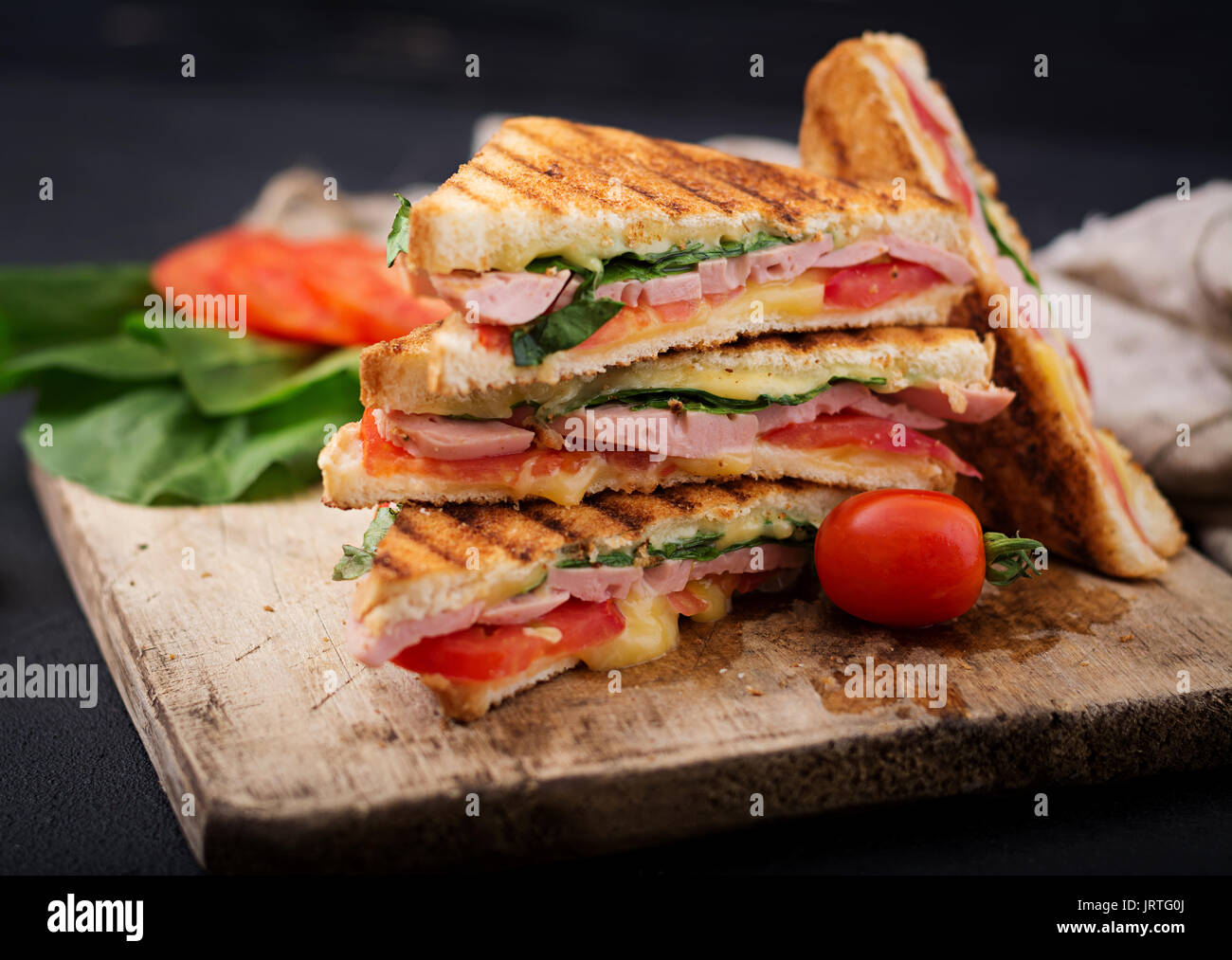 Club Sandwich Panini mit Schinken, Tomaten, Käse und Basilikum. Stockfoto