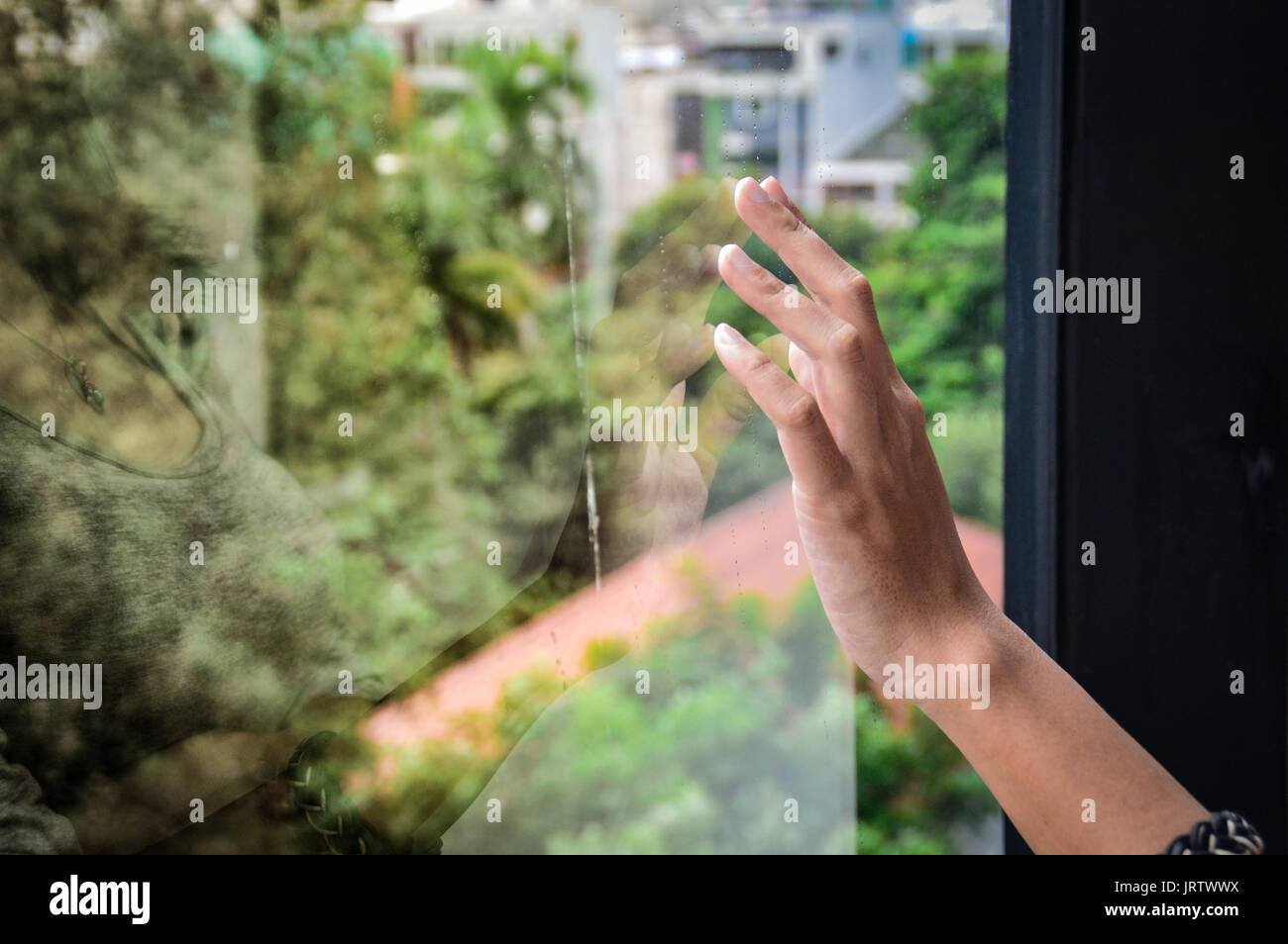 Reflexion der menschlichen Hand berühren ein Glas Fenster mit dem Konzept der Sehnsucht und Traurigkeit Stockfoto