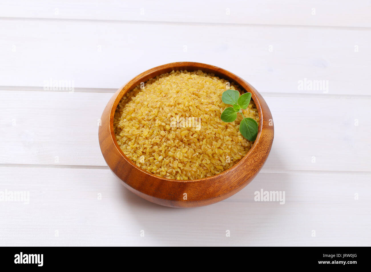 Schüssel mit trockenen Weizen Bulgur auf weißem Holz- Hintergrund Stockfoto