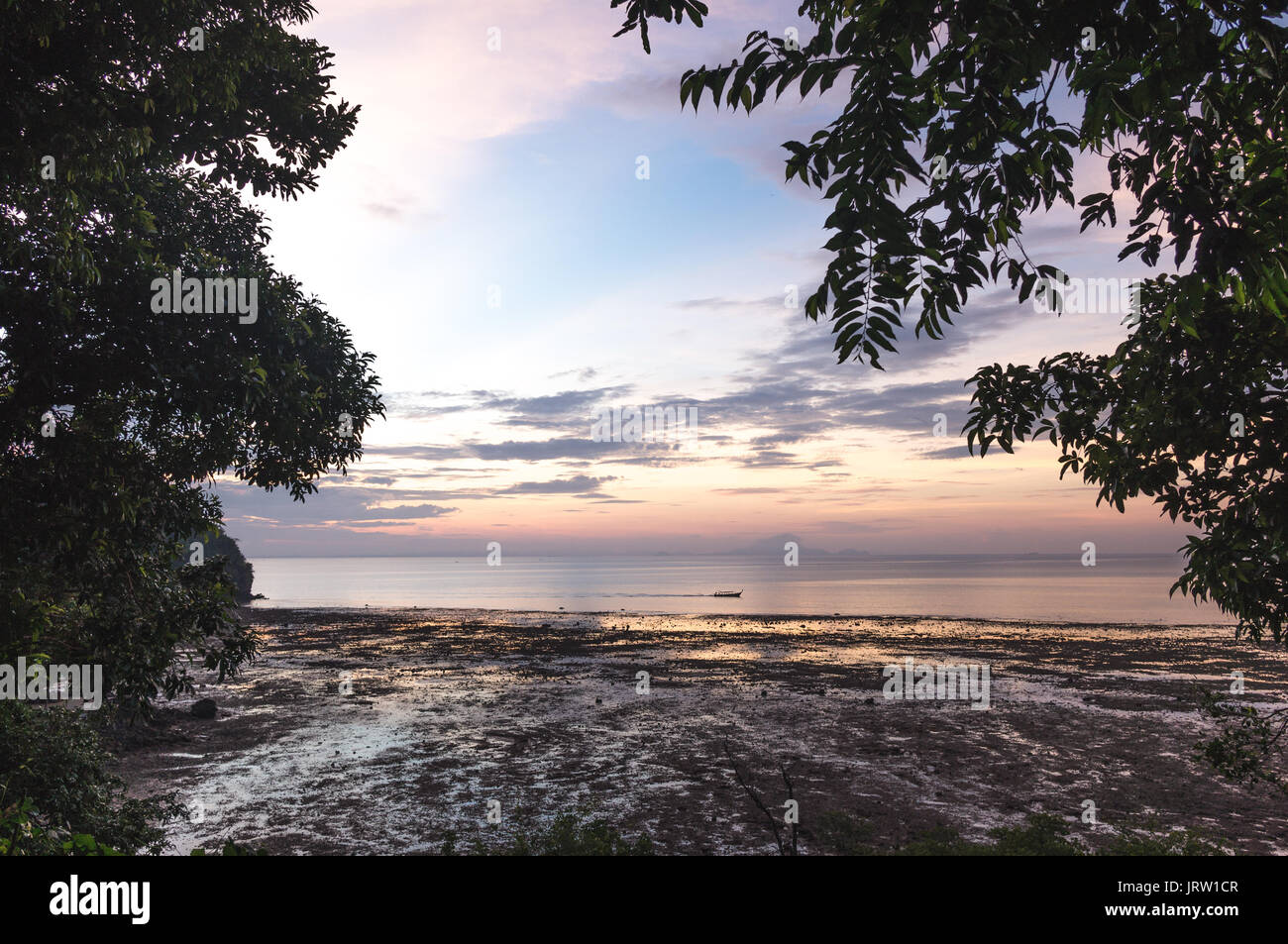 Bunte sunrise von Railay Beach mit einem traditionellen Long tail Boot im Meer. Stockfoto