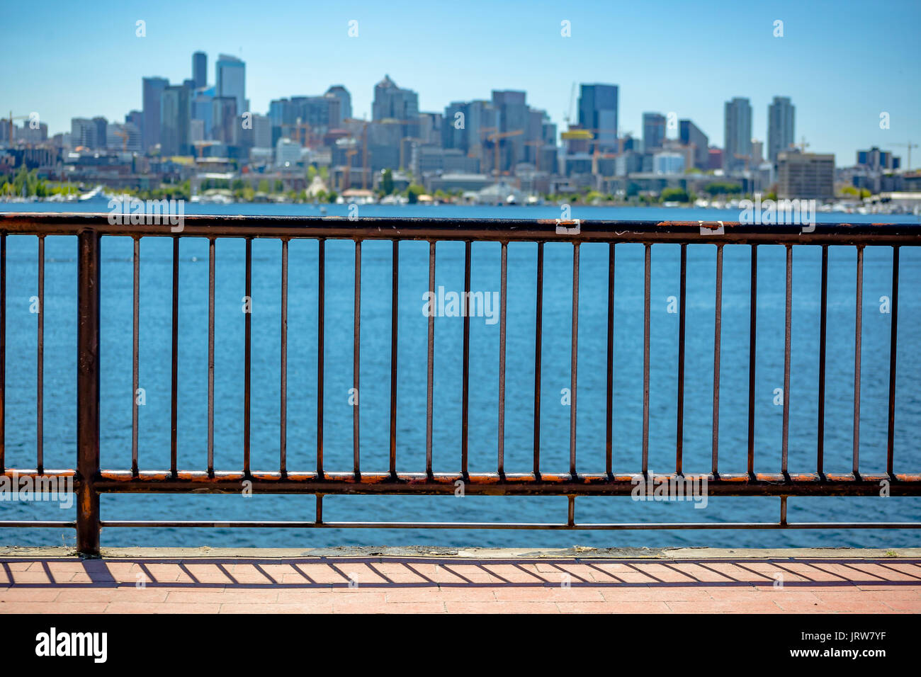 Sonne über der Innenstadt von Seattle mit Elliott Bay und eine Leitplanke im Vordergrund. Seattle Seattle mit Elliott Bay und eine Leitplanke in der foreg Stockfoto