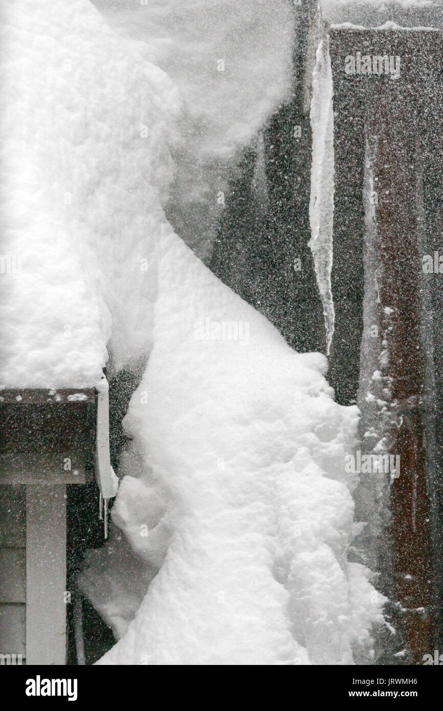 Schnee und Eiszapfen auf einem Dach, während ein Wintersturm Stockfoto