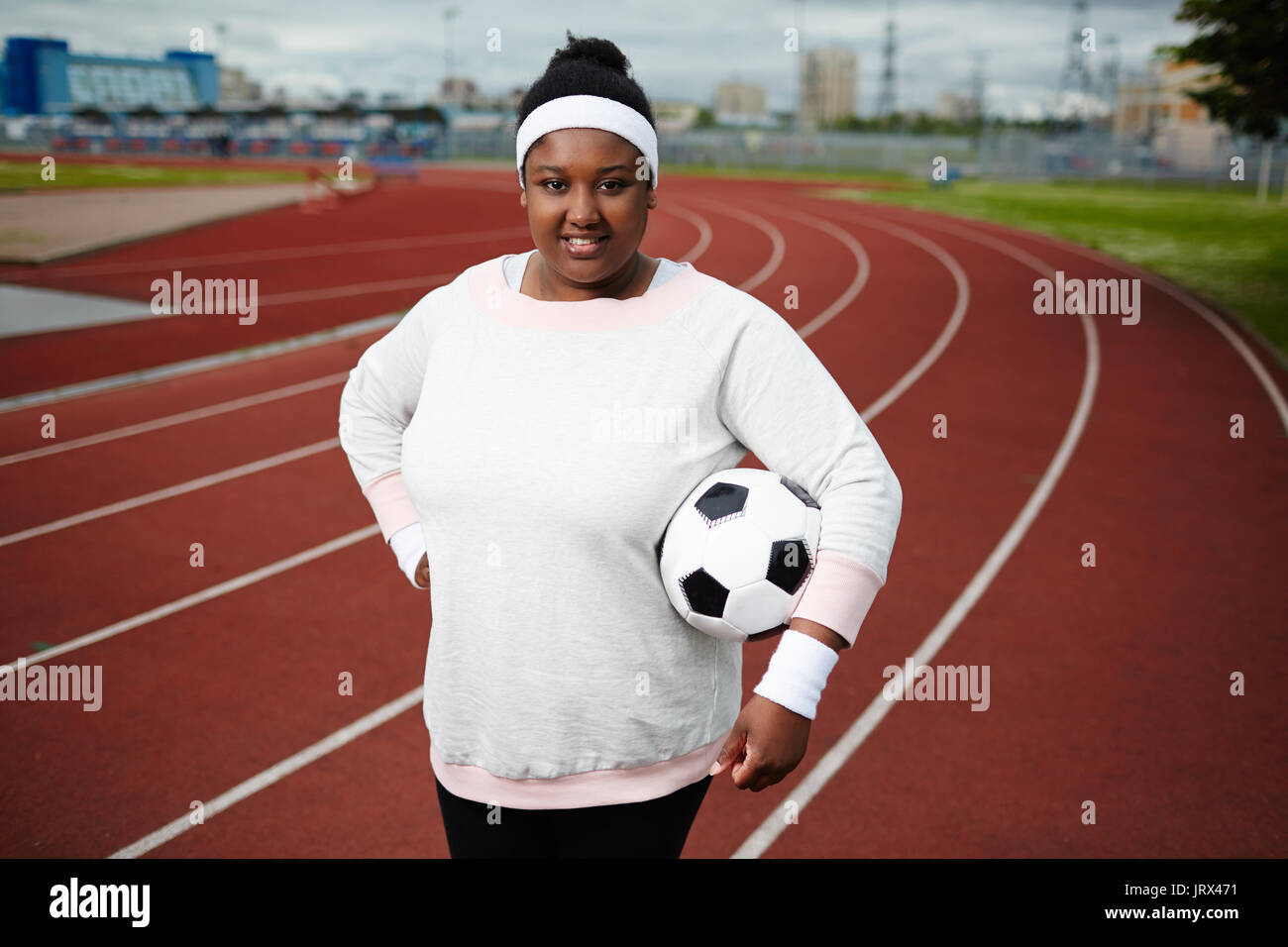 Mollige Frau mit Fußball, Leichtathletik Stadion posing Stockfoto