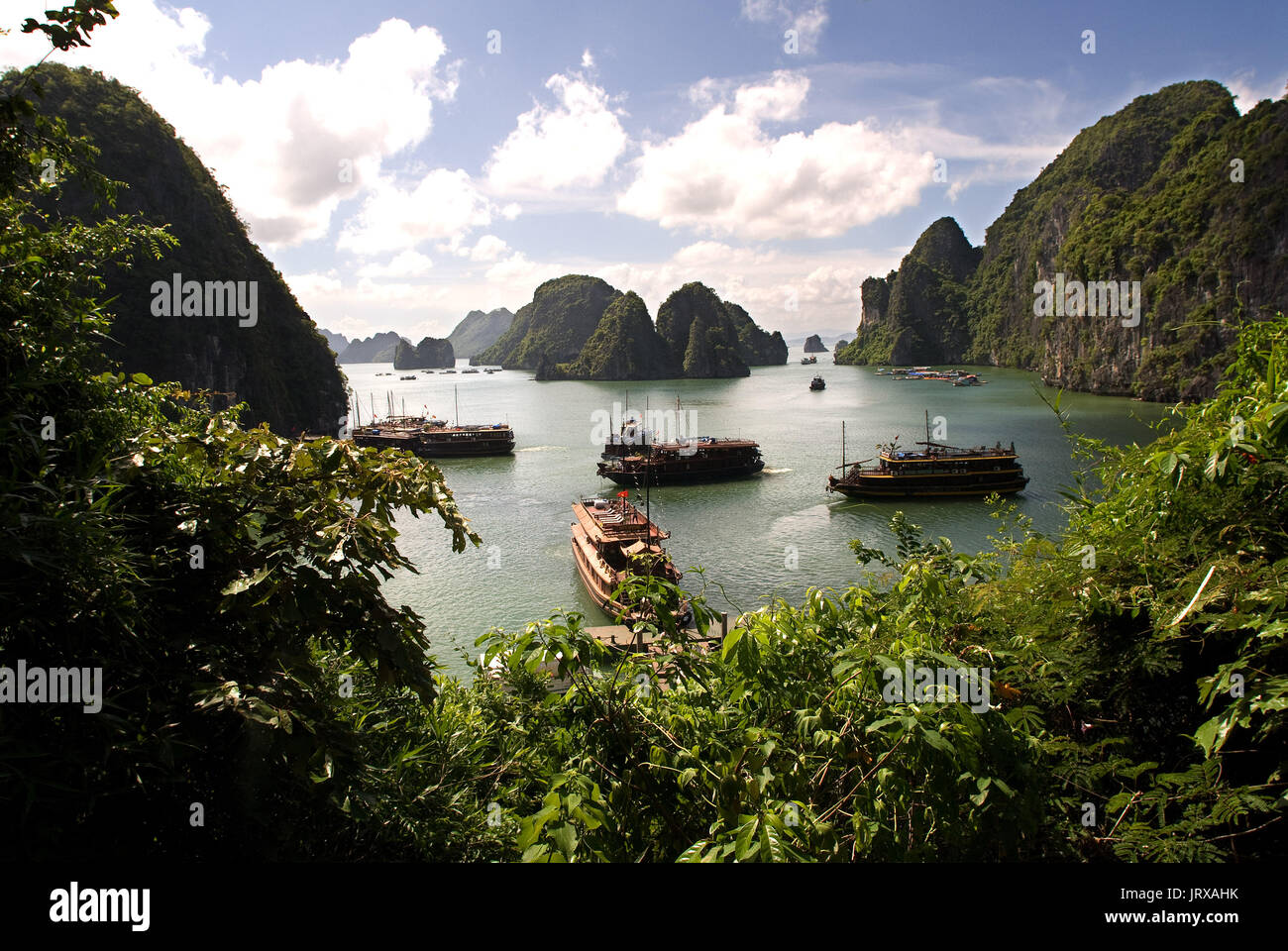 Schiffe, die in der Halong Bucht in der Nähe von Sot Höhle gesungen hängen. ein Bergsteiger Punkte zu den Kalksteinfelsen in der Halong Bay, Vietnam. dschunken in der Halong Bucht in Vietnam Stockfoto