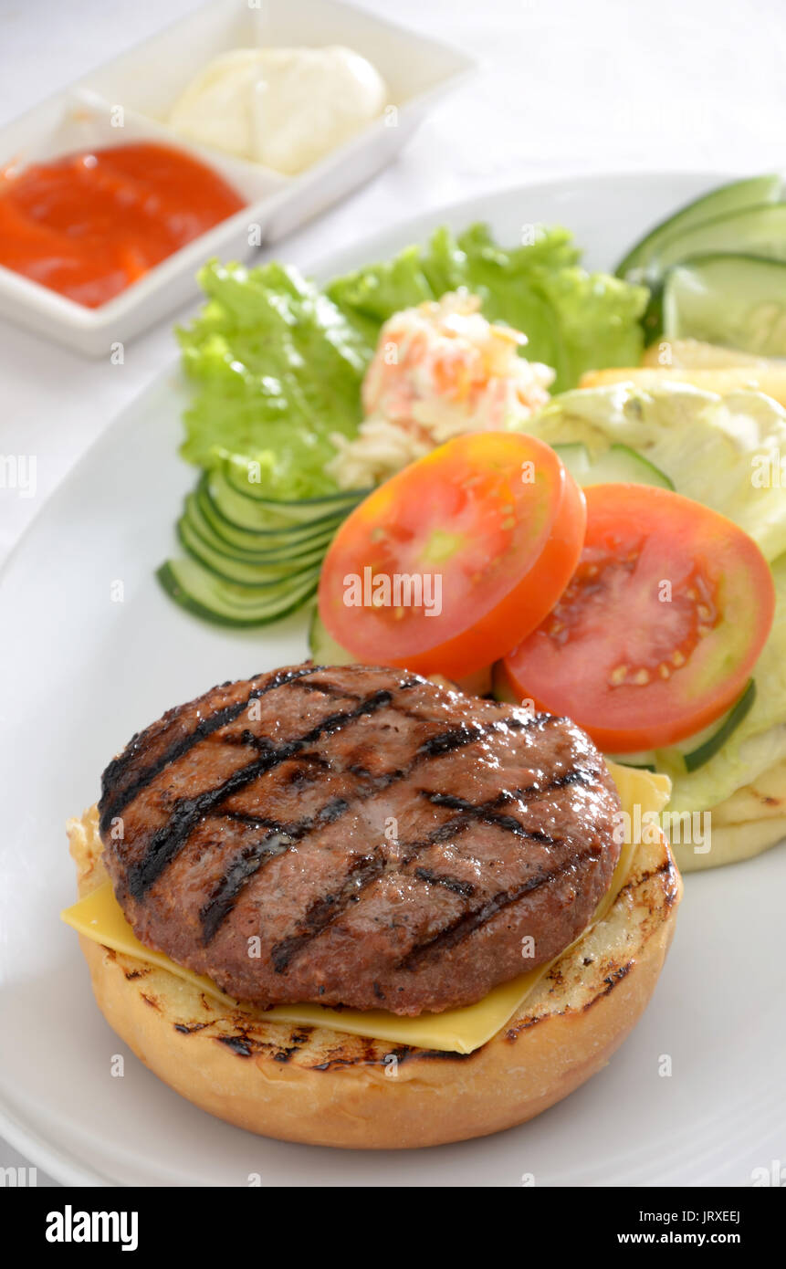 Beef Burger mit Käse Gemüsegarnitur und Chili Sauce und Mayonaise Stockfoto