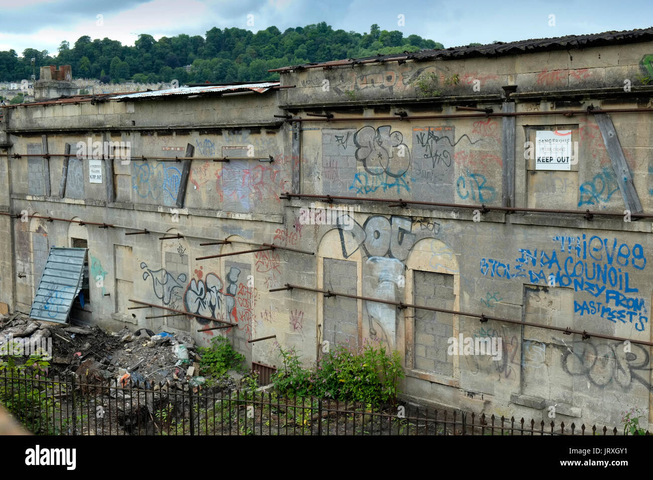 Heruntergekommene, zerstörte Häuser mit Graffiti am Ende der Hampton Zeile in der Mitte der Stadt Bath, UK, mit einer Fußgängerbrücke überqueren der wichtigsten London Stockfoto