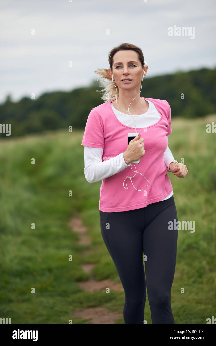 Konzentrierte Frau Musikhören durch Feld, Textfreiraum nach links laufen Stockfoto